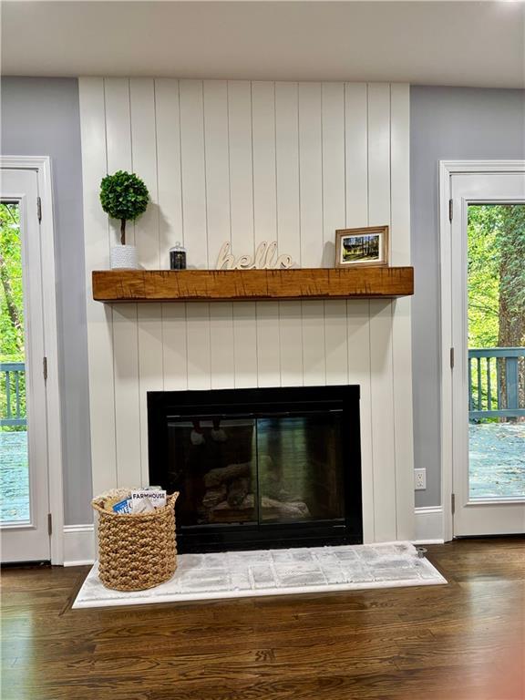 detailed view of a glass covered fireplace, wood finished floors, and baseboards
