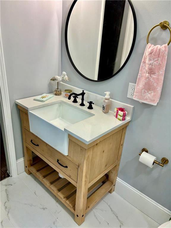 bathroom with marble look tiles, vanity, and baseboards