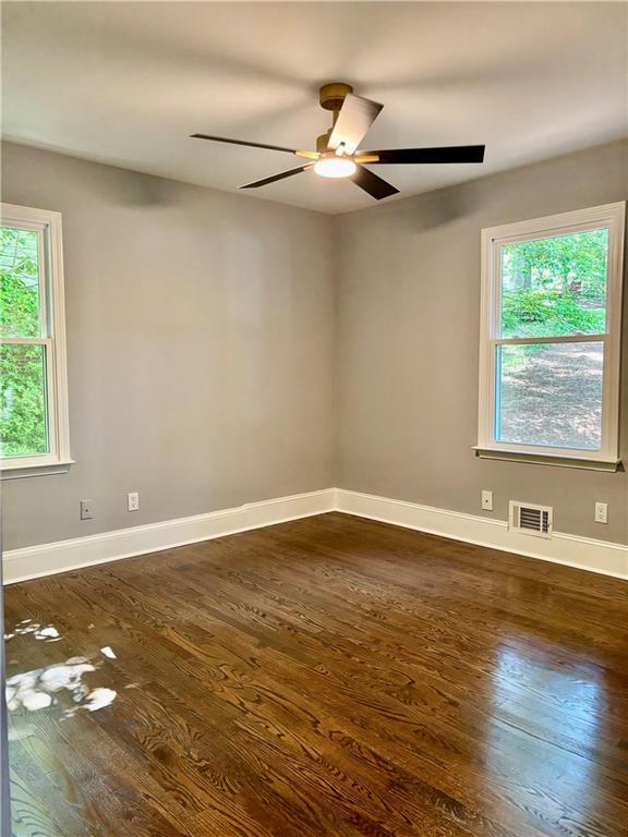 spare room with dark wood-type flooring, healthy amount of natural light, and ceiling fan