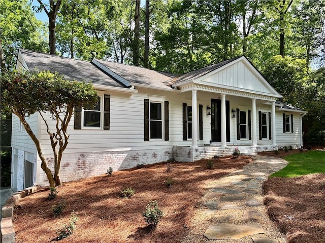 neoclassical home with covered porch, a shingled roof, board and batten siding, and a garage