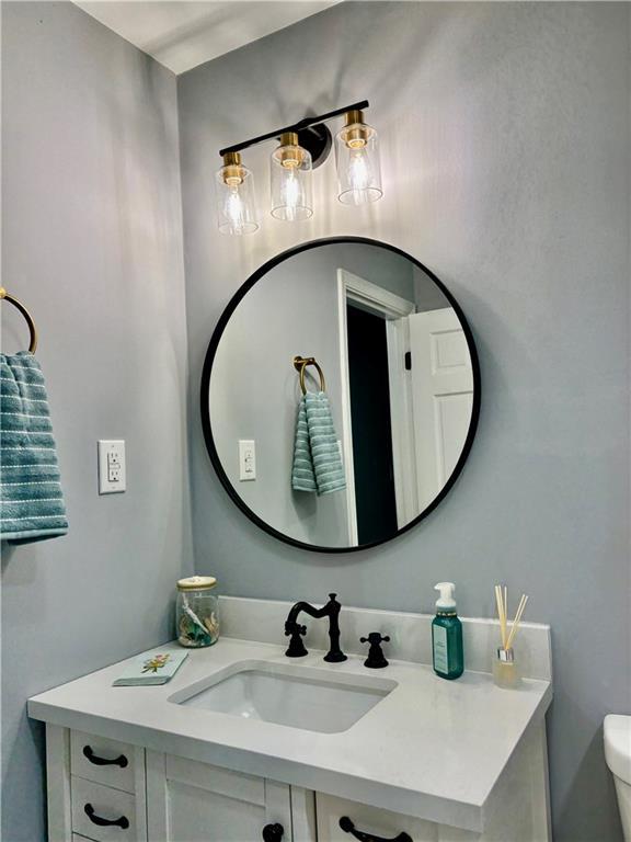 half bath featuring vanity and toilet