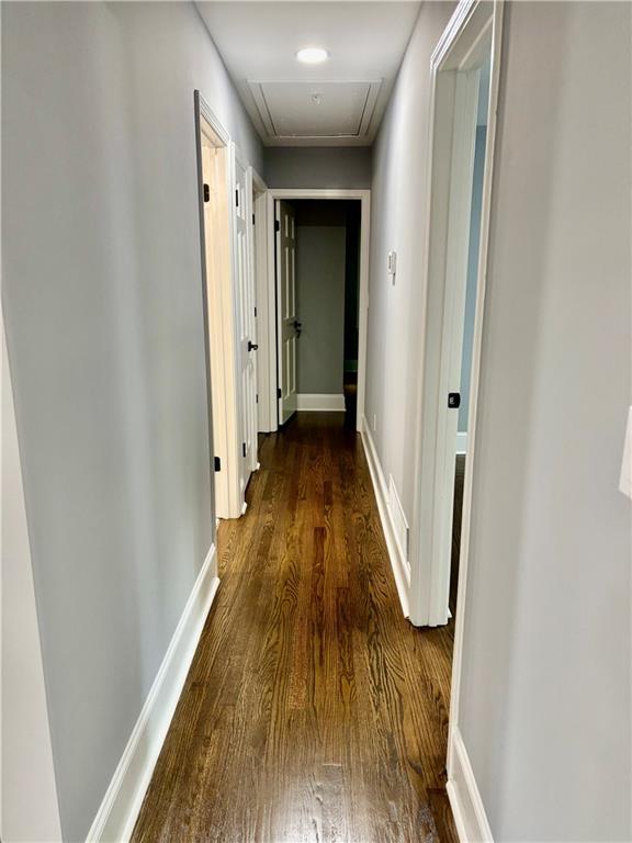 hall with attic access, wood finished floors, and baseboards