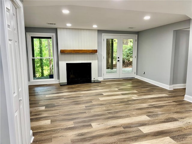 unfurnished living room with baseboards, plenty of natural light, wood finished floors, a large fireplace, and recessed lighting