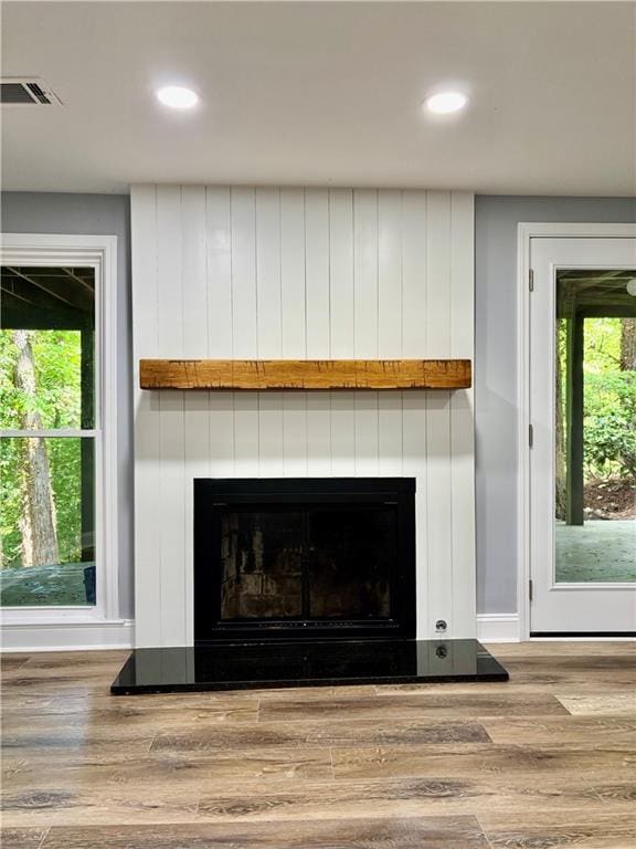 detailed view of a large fireplace, wood finished floors, and recessed lighting