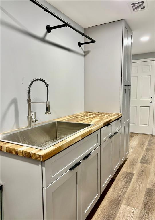 kitchen with wooden counters, a sink, and light wood finished floors