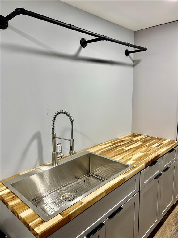 kitchen view of butcher block countertops, a sink, and gray cabinetry