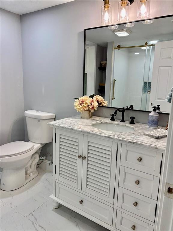 bathroom featuring marble finish flooring, toilet, vanity, and baseboards