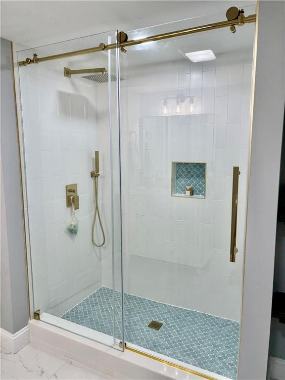 bathroom with a stall shower, marble finish floors, and baseboards