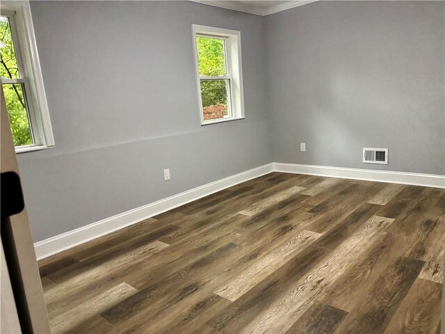 empty room featuring crown molding, baseboards, and dark wood finished floors