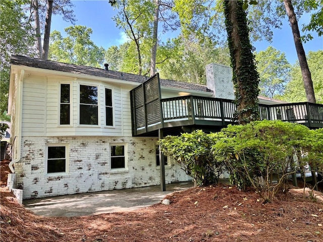 rear view of property with a wooden deck, brick siding, a patio area, and central AC