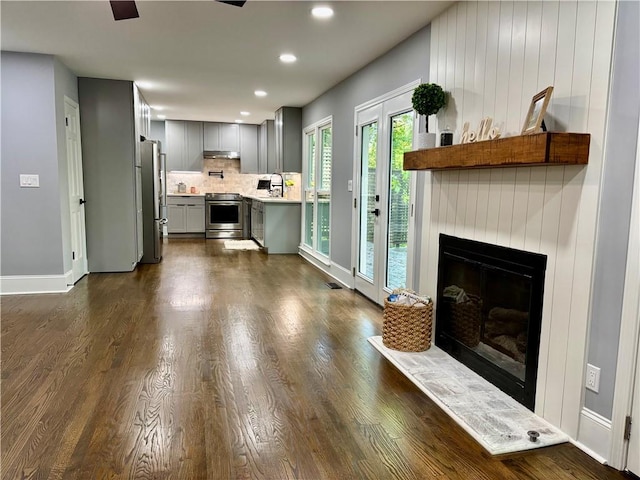 living room featuring baseboards, dark wood-type flooring, recessed lighting, and a glass covered fireplace
