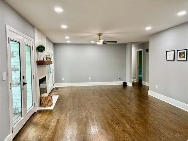 unfurnished living room with a ceiling fan, recessed lighting, dark wood-style flooring, a glass covered fireplace, and baseboards