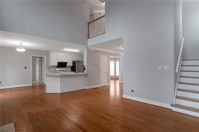 2157 Brandon Lee Dr SW, Marietta, GA 30008 - unfurnished living room featuring a towering ceiling, baseboards, wood finished floors, and stairs