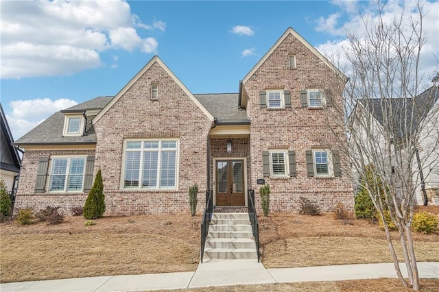 view of front of home with brick siding, roof with shingles, and french doors