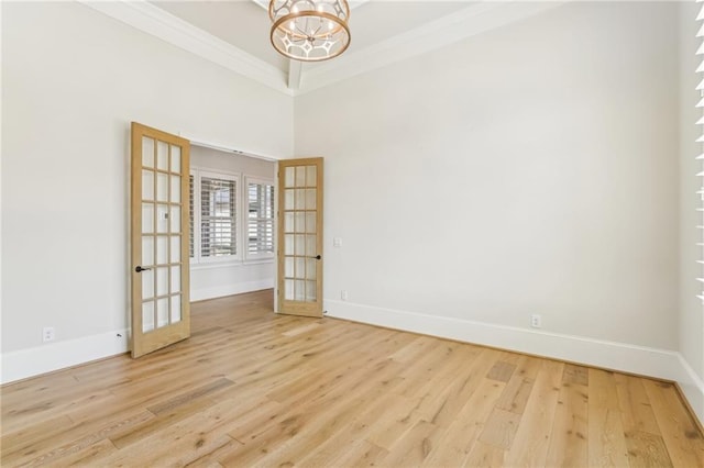 spare room featuring crown molding, baseboards, wood finished floors, and french doors