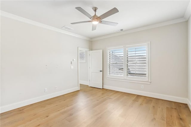 spare room with light wood-type flooring, baseboards, visible vents, and crown molding