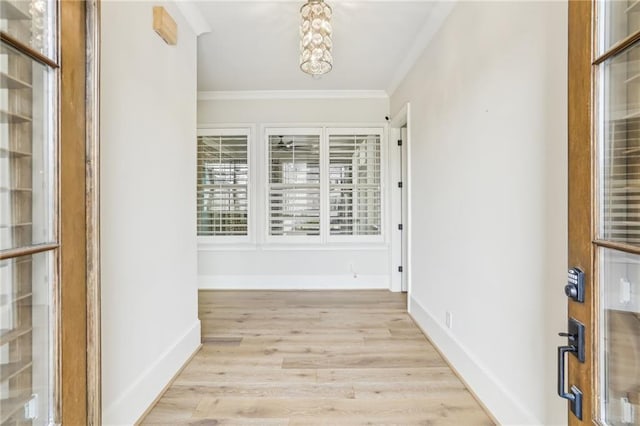 interior space featuring ornamental molding, baseboards, and light wood finished floors