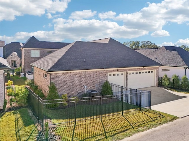 view of side of property with driveway, a lawn, an attached garage, fence, and brick siding