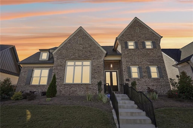 traditional-style home featuring french doors, brick siding, and a lawn