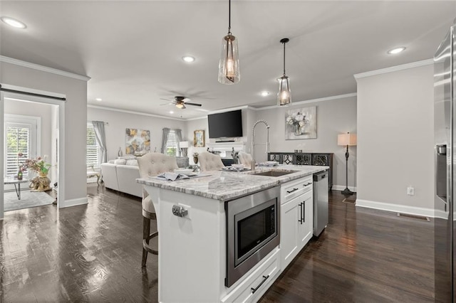 kitchen with open floor plan, crown molding, appliances with stainless steel finishes, and a sink