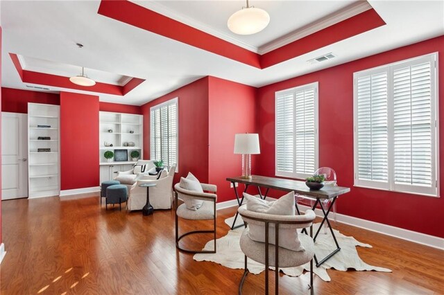 sitting room with ornamental molding, wood-type flooring, and a tray ceiling