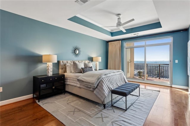 bedroom with a raised ceiling, hardwood / wood-style flooring, access to exterior, and ceiling fan