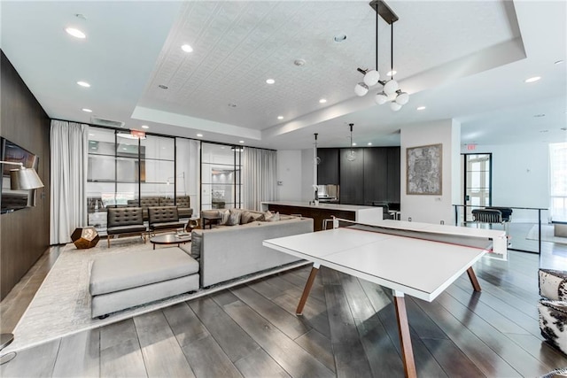 rec room with dark wood-type flooring and a tray ceiling