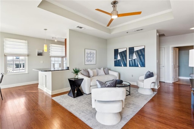 living room featuring a raised ceiling, hardwood / wood-style flooring, and ceiling fan