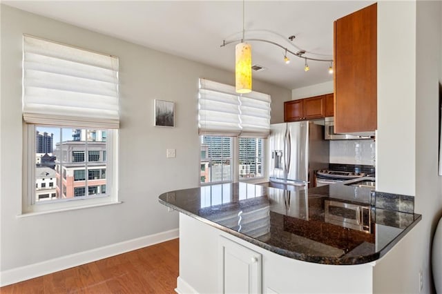 kitchen featuring appliances with stainless steel finishes, kitchen peninsula, and dark stone countertops