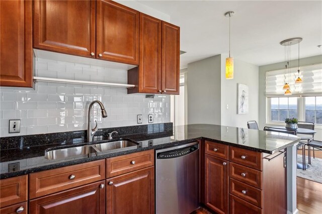 kitchen with sink, dark stone countertops, decorative backsplash, hanging light fixtures, and stainless steel dishwasher