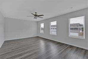 empty room with ceiling fan, plenty of natural light, and wood finished floors