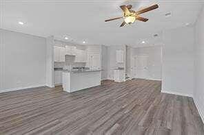 unfurnished living room featuring dark wood finished floors and a ceiling fan