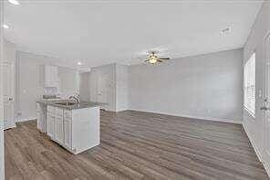 kitchen with a kitchen island with sink, white cabinetry, open floor plan, and dark wood-type flooring