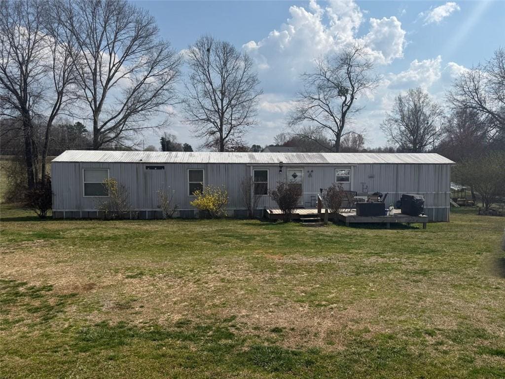 rear view of house featuring a wooden deck and a lawn