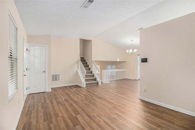 interior space with a textured ceiling, a chandelier, dark hardwood / wood-style floors, and lofted ceiling