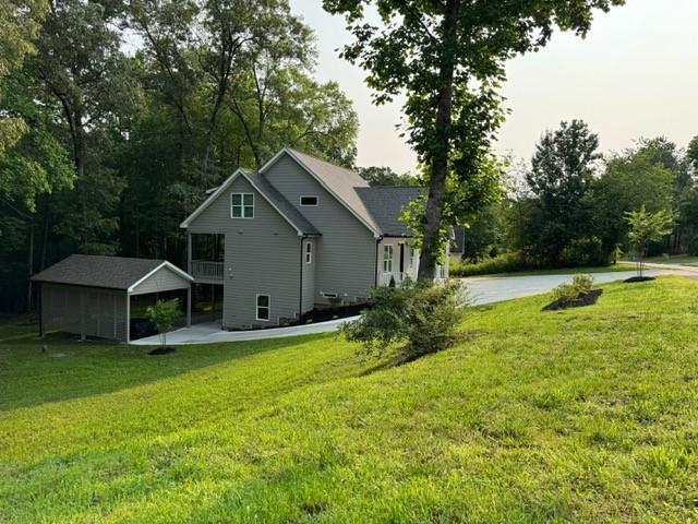 1713 Cagle Ct, Lawrenceville, GA 30045 - back of house featuring a lawn, an outbuilding, and view of scattered trees