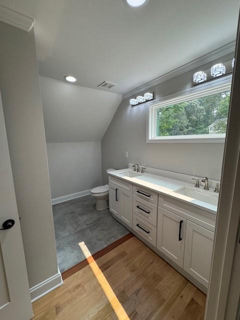 1713 Cagle Ct, Lawrenceville, GA 30045 - bathroom featuring lofted ceiling, double vanity, toilet, crown molding, and baseboards