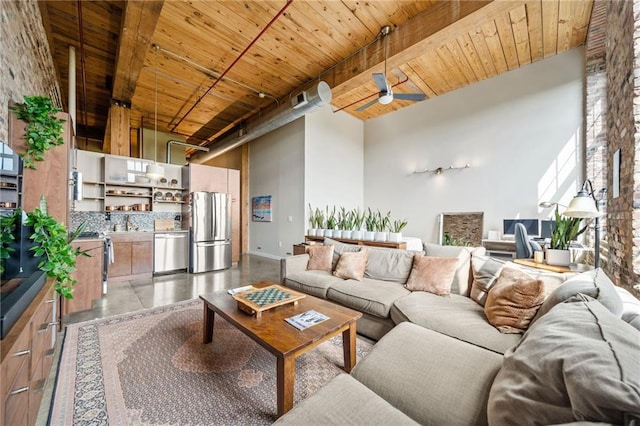 living room with beam ceiling, a towering ceiling, wooden ceiling, and ceiling fan