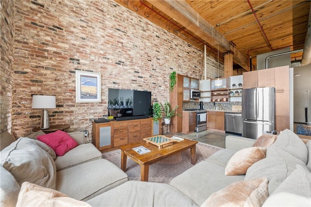 living room with beam ceiling, wooden ceiling, brick wall, and a high ceiling