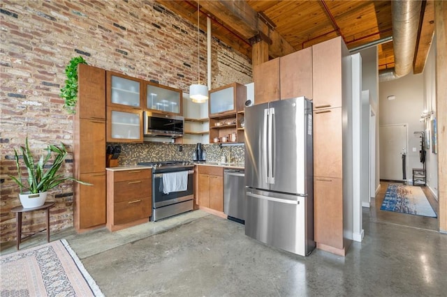 kitchen with brick wall, a towering ceiling, decorative light fixtures, tasteful backsplash, and stainless steel appliances