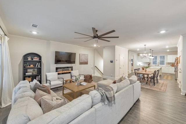 living room featuring crown molding, sink, ceiling fan with notable chandelier, and hardwood / wood-style floors