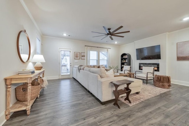 living room featuring dark wood-type flooring, ornamental molding, and ceiling fan