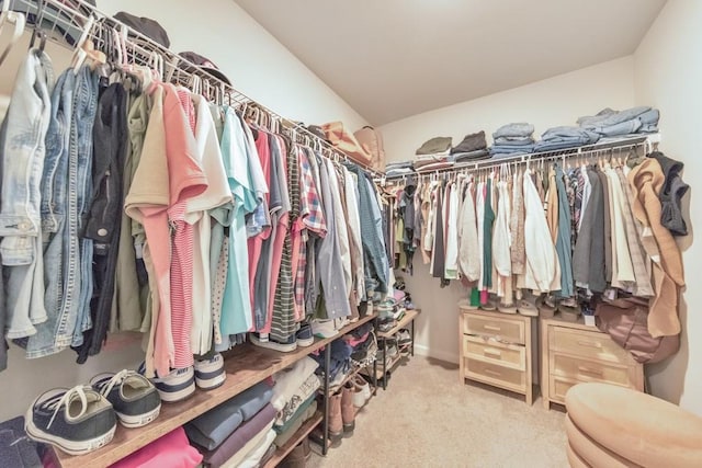 spacious closet with lofted ceiling and light colored carpet