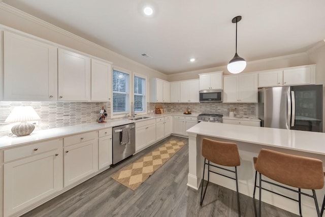 kitchen with hanging light fixtures, white cabinetry, appliances with stainless steel finishes, and a breakfast bar area