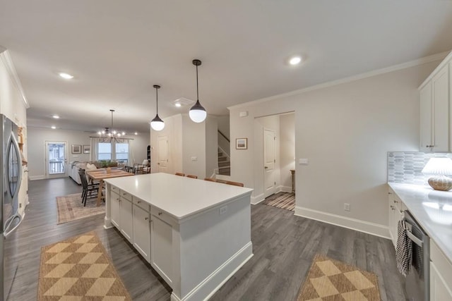 kitchen with white cabinetry, a center island, ornamental molding, and decorative light fixtures