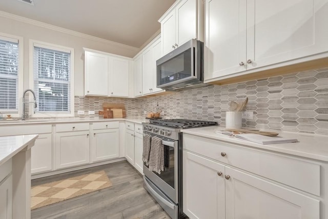 kitchen featuring sink, crown molding, appliances with stainless steel finishes, a healthy amount of sunlight, and white cabinets