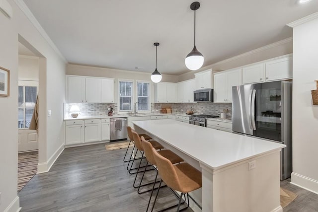 kitchen featuring sink, white cabinetry, appliances with stainless steel finishes, a kitchen island, and pendant lighting