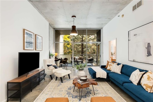 living room with floor to ceiling windows, visible vents, and concrete floors