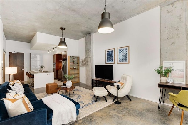 living room featuring rail lighting and concrete floors