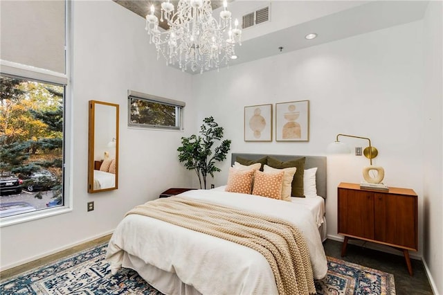 bedroom with baseboards, a chandelier, a high ceiling, and visible vents